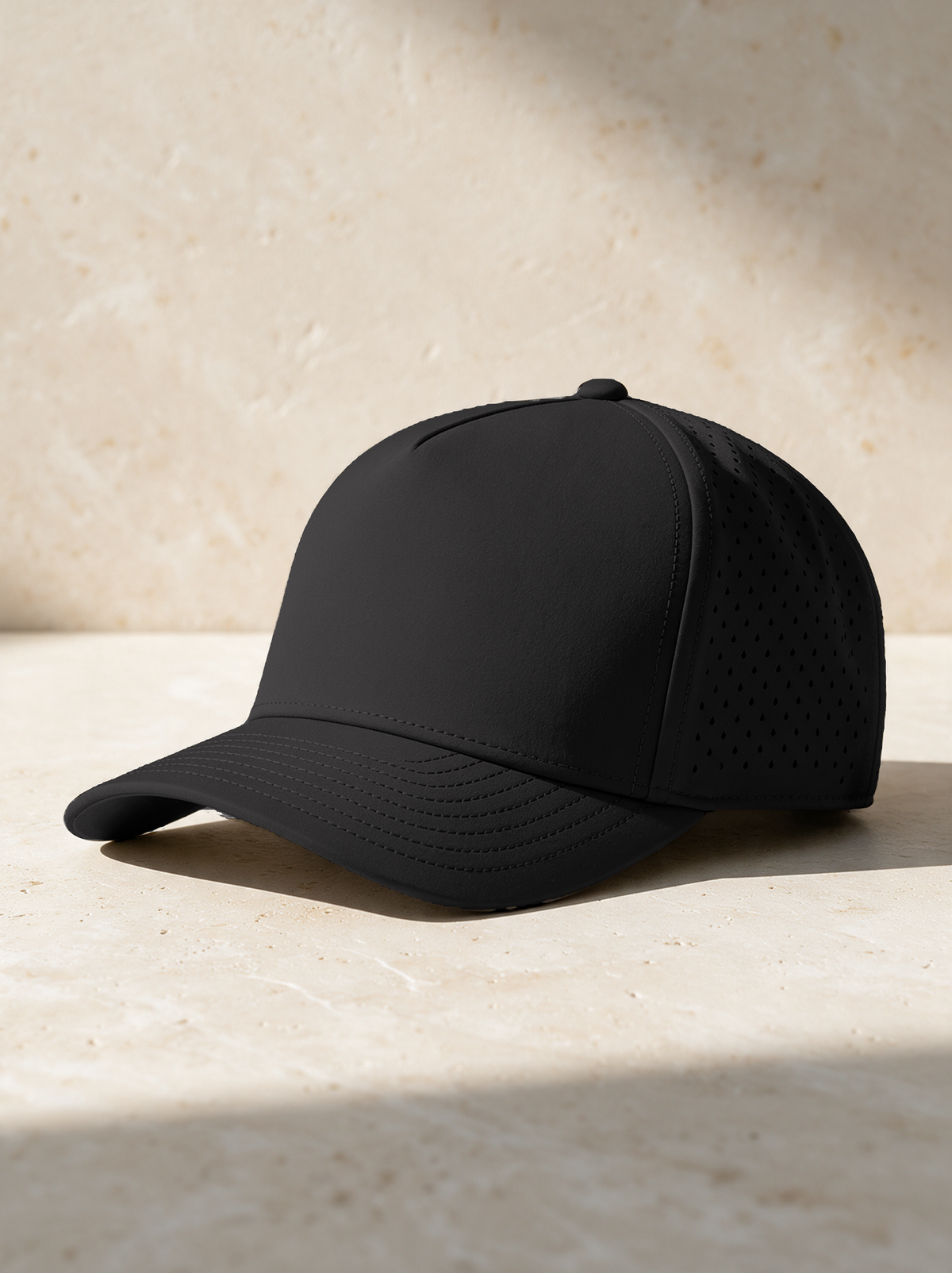 The Performance Cap in black, on warm stone